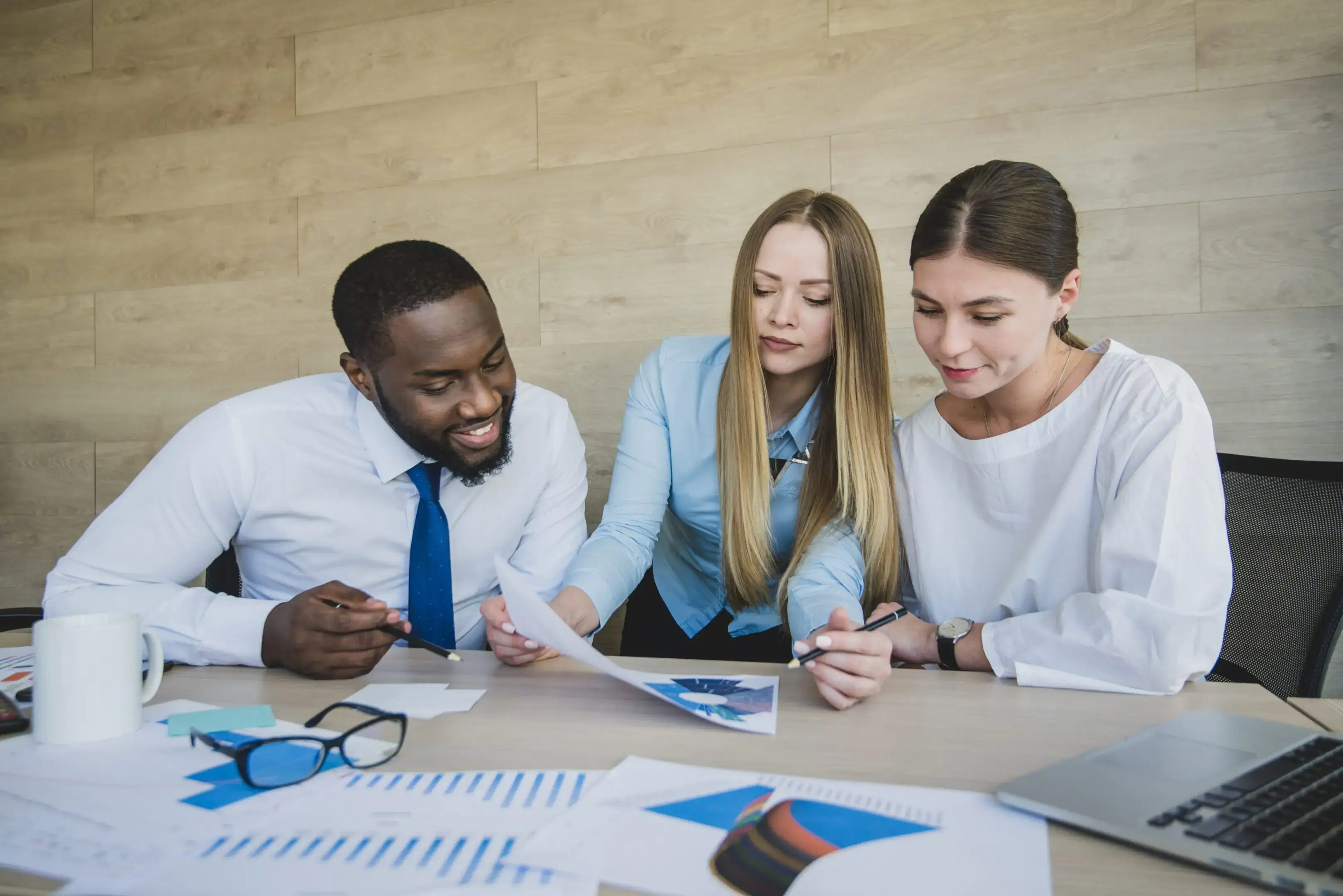 Colleagues discussing documents at a meeting table.